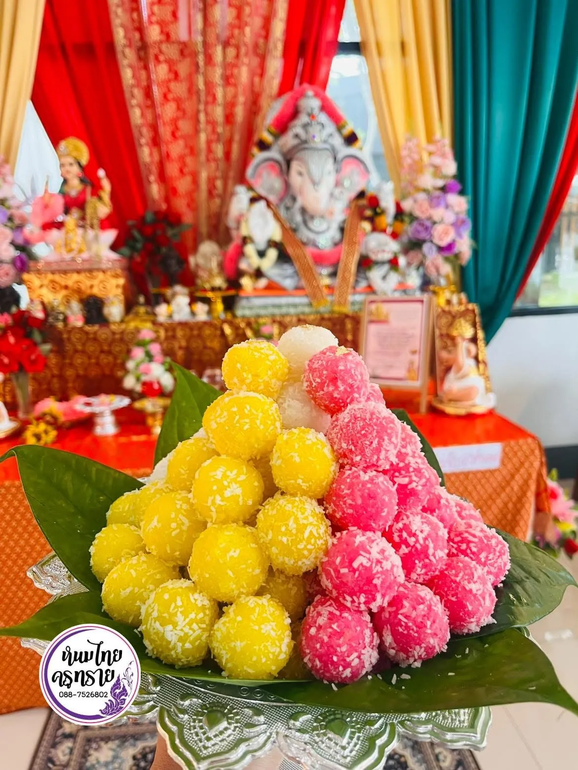 ขนมลาดูสีเหลืองและสีชมพูจัดเป็นทรงสูงบนพาน หน้าห้องบูชาพระพิฆเนศ